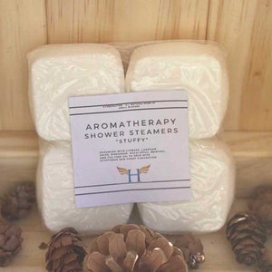 K&ouml;nnte beinhalten: Vier wei&szlig;e Aromatherapie-Duschdampfer in einer durchsichtigen Plastikt&uuml;te mit einem Etikett mit der Aufschrift "Aromatherapy Shower Steamers *Stuffy* Enhanced with Cypress, Camphor, Anise, Marjoram, Eucalyptus, Menthol, and Tea Tree Oil to help with stuffiness and chest congestion H"