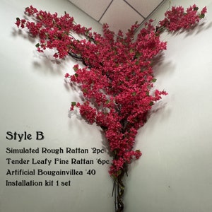 May include: A pink artificial bougainvillea vine with green leaves, hanging from a corner of a white wall. The vine is made of plastic and has a realistic appearance. The text "Style B" is written below the vine, along with a list of materials and quantities: "Simulated Rough Rattan 2pc", "Tender Leafy Fine Rattan 6pc", "Artificial Bougainvillea '40", and "Installation kit 1 set".