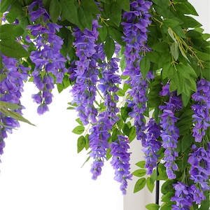 May include: Artificial wisteria vines with cascading purple flowers and green leaves. The wisteria is a popular decorative element for weddings, parties, and home decor. The image shows a close-up of the wisteria, highlighting the details of the flowers and leaves.