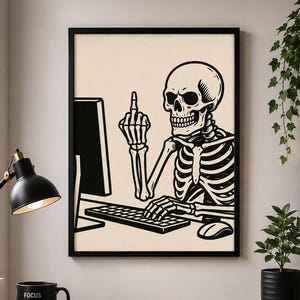 May include: A framed black and white graphic art print featuring a skeleton sitting at a computer, typing on a keyboard with one hand whilst holding up its middle finger with the other. The illustration uses bold lines and a cream-coloured background.