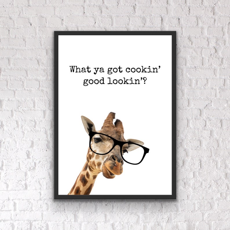 May include: A framed print featuring a giraffe wearing black glasses. The text above the giraffe reads, "What ya got cookin' good lookin'?" The giraffe has a brown and tan spotted pattern.