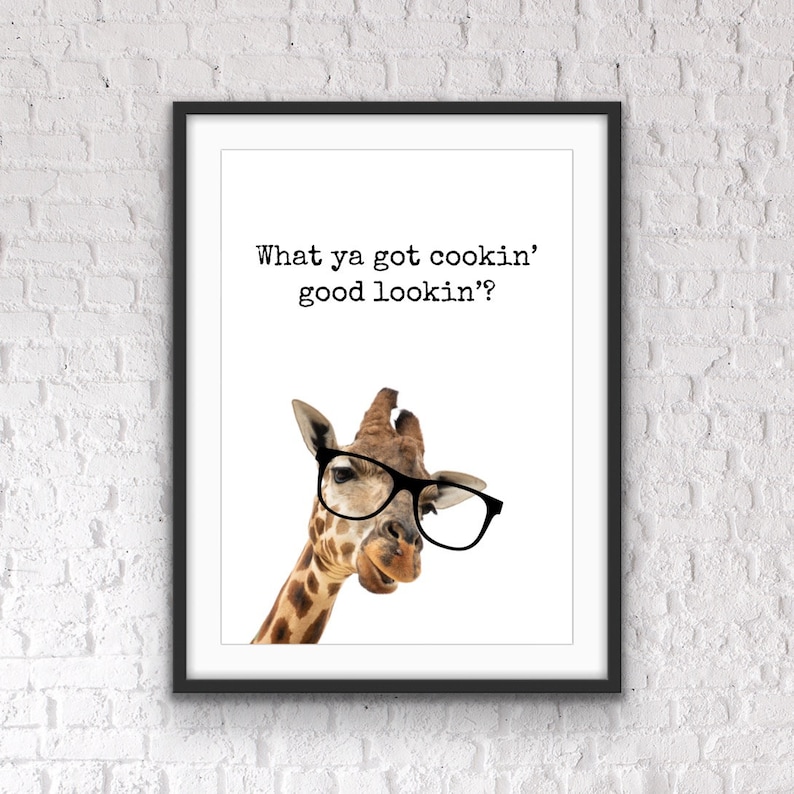 May include: Framed art print featuring a giraffe wearing black glasses. The giraffe is brown and white with a long neck. The print has the text "What ya got cookin' good lookin'?" in black font on a white background.