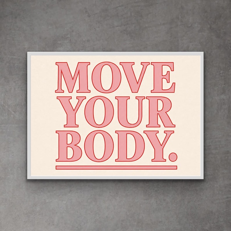 May include: A framed print with the words "MOVE YOUR BODY" in a bold, pink font. The text is centered on a cream-colored background, with a pink line beneath the words. The frame is white, and the overall aesthetic is modern and motivational.