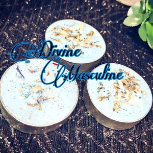 May include: Three blue tealight candles with a light blue wax base and a variety of dried herbs and flowers embedded in the wax. The candles are labeled "Divine Masculine".
