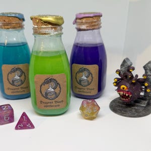 May include: Three glass bottles filled with blue, green, and purple liquids, each with a cork top and a label that reads "Dragons Blood apothecary." A purple die, a pink triangular die, a yellow die, and a purple monster figurine are also present.