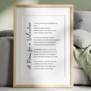 Peut inclure: Une impression encadrée avec un cadre en bois clair. L'impression présente un poème intitulé "A Poem for a Volunteer" en script noir. Le poème est centré sur un fond blanc. L'impression est affichée sur un canapé gris avec des oreillers et une couverture verte.