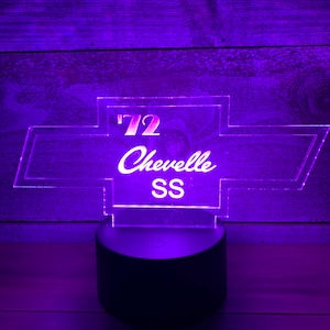 May include: A purple illuminated acrylic sign with a Chevrolet logo and the text '72 Chevelle SS'. The sign is on a black base.