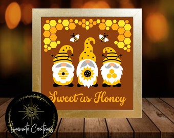 May include: Three gnomes with yellow and black bee-themed hats and beards stand in front of a brown background with a honeycomb pattern. The gnomes are wearing yellow and black striped shirts and have a sunflower, a honeycomb, and a beehive on their bellies. The text "Sweet as Honey" is written below the gnomes.