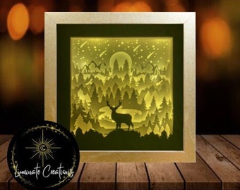 Puede incluir: Una escena nocturna iluminada en papel recortado en 3D con un ciervo de pie en un bosque con luna llena y estrellas fugaces en el cielo.