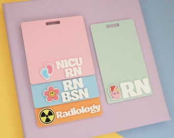 May include: Four rectangular badge reels in pink, light blue, orange, and mint green. The pink one says NICU RN with baby feet, the blue one says RN BSN with a flower, the orange one says Radiology with a radiation symbol, and the mint one says RN with a heart.