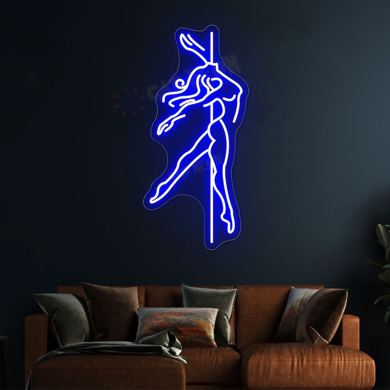 K&ouml;nnte beinhalten: Blaues Neon-Schild, das eine Frau darstellt, die an einer Stange tanzt. Das Schild ist an einer dunkelblauen Wand &uuml;ber einem braunen Sofa angebracht.