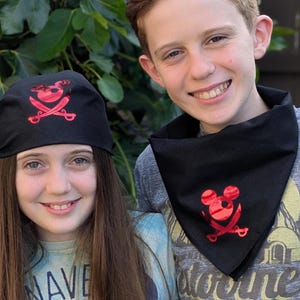May include: Black pirate bandana and cap set with a red skull and crossbones design. The cap is worn on the head, and the bandana is around the neck. The set is suitable for costume parties or themed events.
