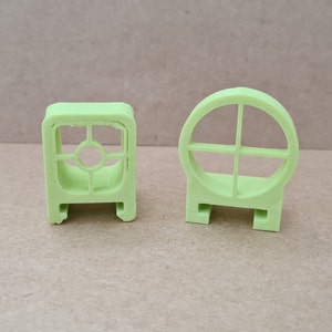 May include: Two lime green plastic 3D printed target shapes. One is a square with a circle in the center and the other is a circle with a crosshair design.