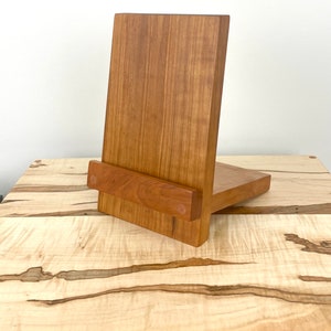 Peut inclure: Un support en bois compos&eacute; d'un panneau arri&egrave;re vertical et d'une tablette horizontale pour maintenir des objets. Le support est fabriqu&eacute; en bois de ton moyen avec un grain visible et deux chevilles en bois circulaires sur le rebord avant.