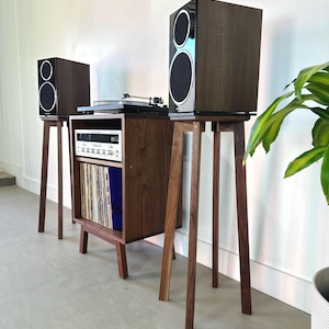 May include: A walnut wood record player stand with a turntable, receiver, and two speakers on stands. The stand has a shelf for storing vinyl records.