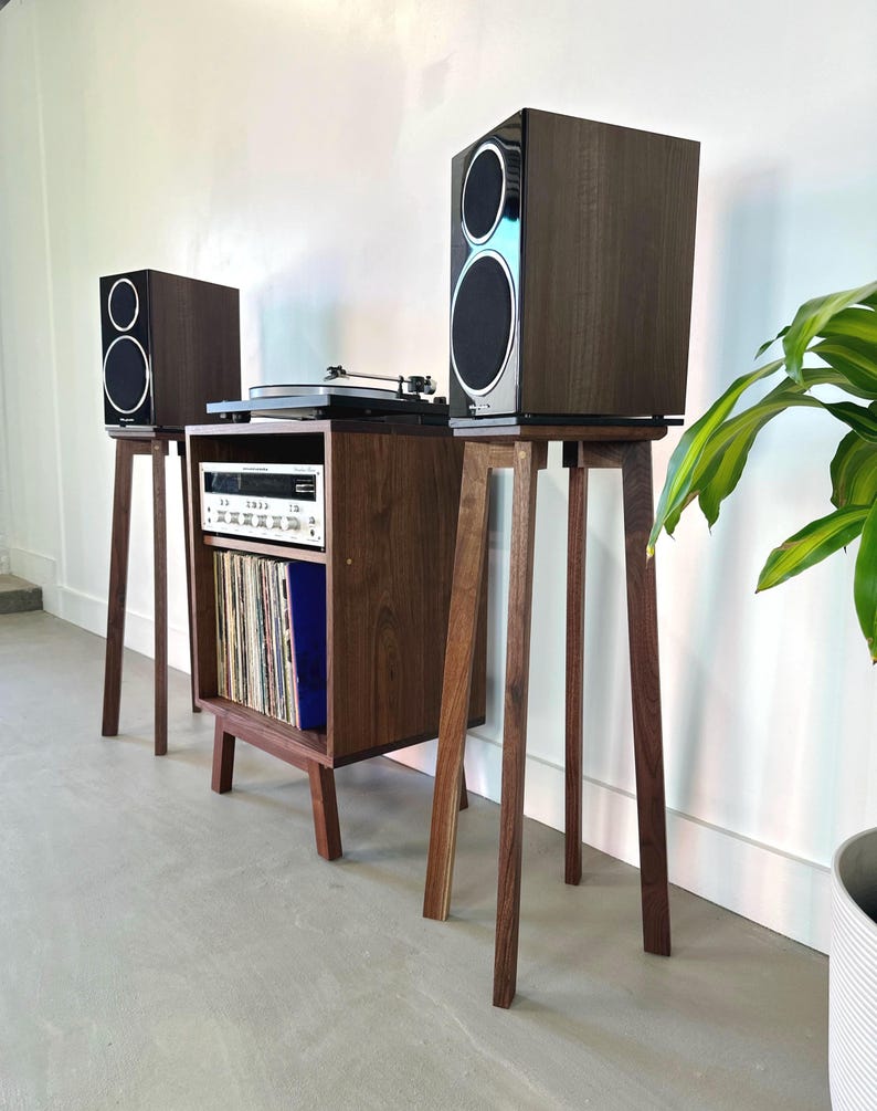 May include: A walnut wood record player stand with a turntable, receiver, and two speakers on stands. The stand has a shelf for storing vinyl records.