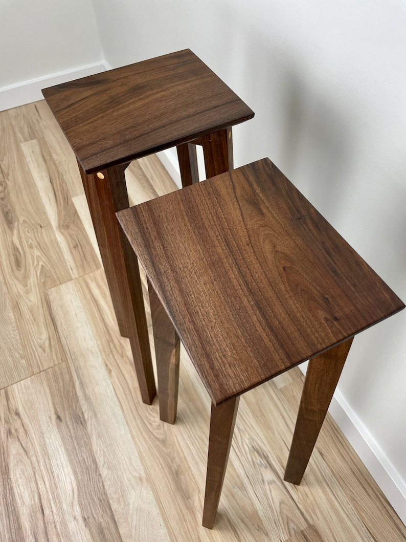 May include: Two wooden nesting tables with a dark brown finish. The tables have a simple design with four legs and a rectangular top.