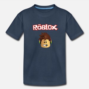 Puede incluir: Una camiseta azul marino con la palabra "ROBLOX" en letras rojas y un personaje de dibujos animados con auriculares.