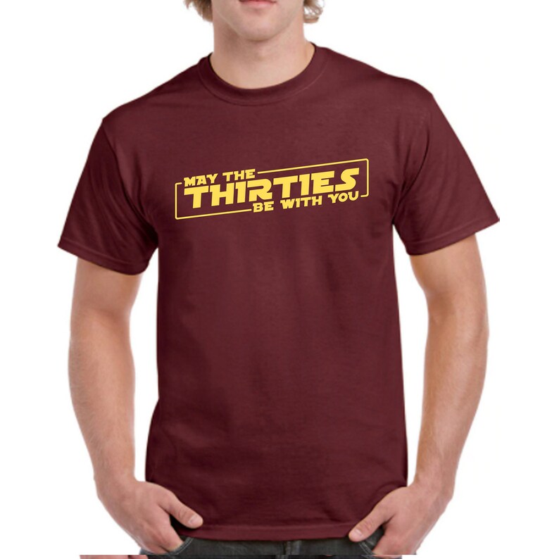 May include: A maroon t-shirt with a yellow graphic that says "May the Thirties Be With You".