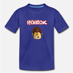 Puede incluir: Una camiseta azul real con un logotipo "ROBLOX" blanco y rojo y un personaje de dibujos animados con auriculares.