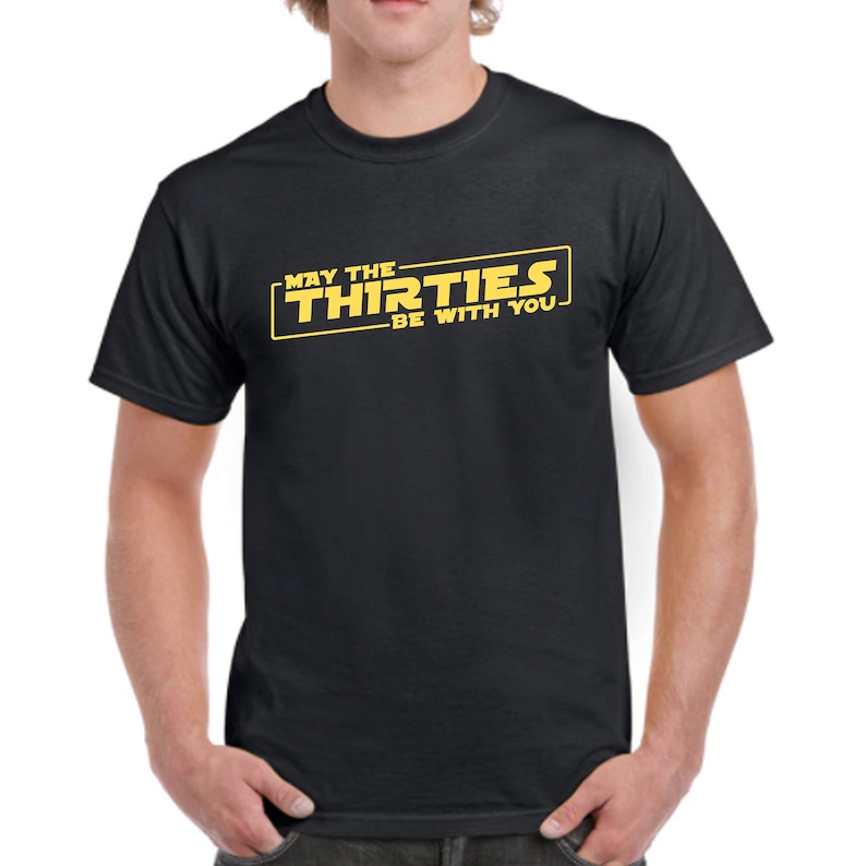 May include: Black t-shirt with a yellow graphic that says "May the Thirties Be With You" in a Star Wars-inspired font.