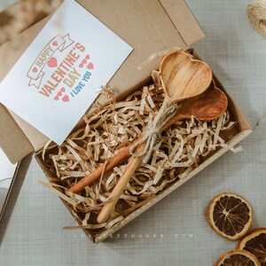 Handmade wooden heart spoon with custom engraving, displayed as guest gifts.