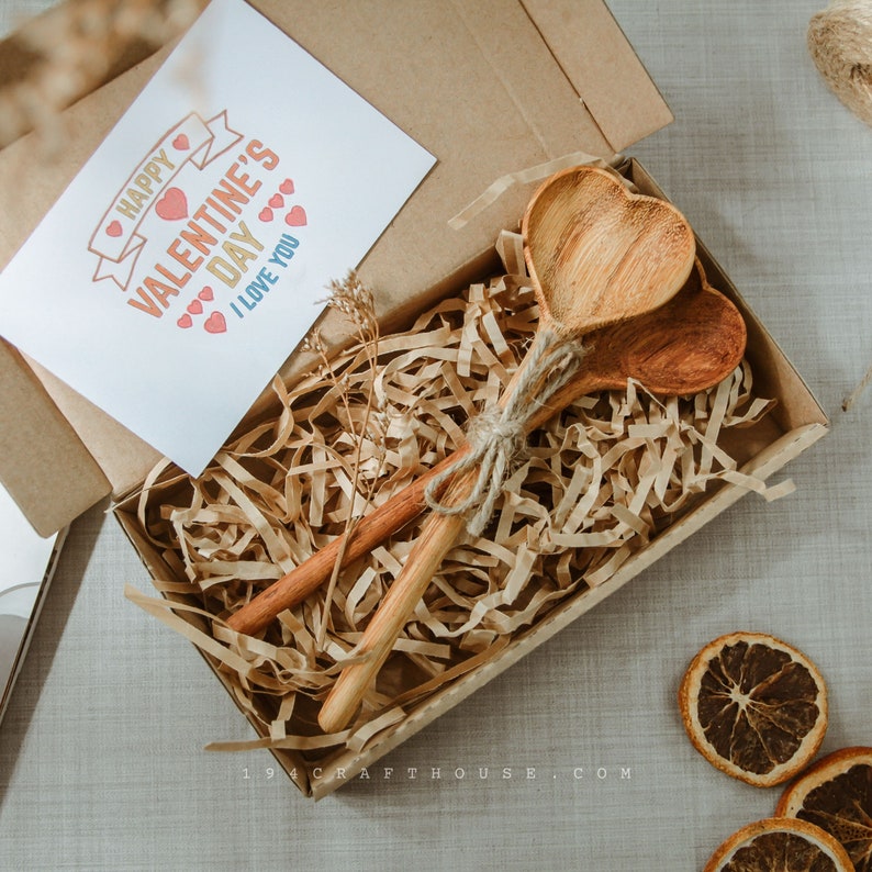 Handmade wooden heart spoon with custom engraving, displayed as guest gifts.