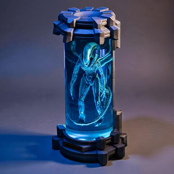 A custom alien creature frozen mid-emergence from glowing epoxy resin and raw wood — sci-fi horror art and functional lamp in one unsettling package.