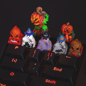 May include: A selection of Halloween-themed keycaps, including ghosts and jack-o'-lanterns, on a black keyboard. The keycaps are brightly coloured with intricate details, featuring hats and spooky designs. The keyboard keys are black with red illuminated lettering.