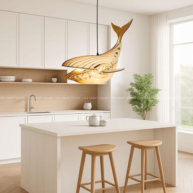 A wooden whale pendant light hangs over a kitchen island embodying Scandinavian decor.