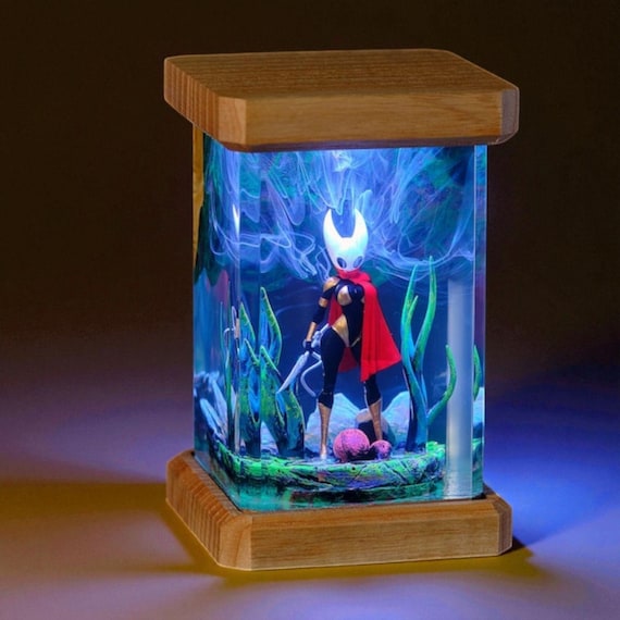 Hollow Knight's iconic silhouette trapped in glowing amber resin — a handmade lamp that doubles as a shrine to an indie gaming classic.