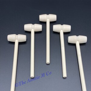 May include: Five wooden mallet toys with white paint. The mallets have a round head and a long, thin handle.