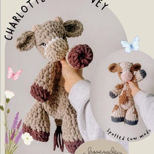 May include: A handmade crochet cow lovey in shades of tan, brown, and burgundy. The cow has a textured body, floppy ears, and a small tail. The text "Charlotte Cow Lovey" is arched above the cow. A smaller spotted cow is also shown.