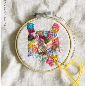 Puede incluir: Primer plano de un proyecto de bordado colorido en un aro de bordado de madera. El bordado es un diseño de patchwork de la cara de un oso. El texto "Embroidery sewed with the darning stitch" está escrito alrededor del aro.