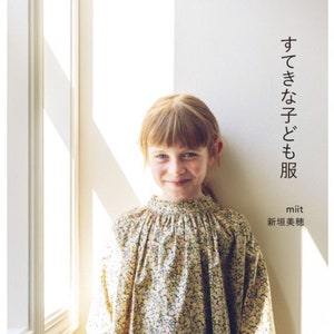 May include: A book cover with a young girl wearing a floral dress. The title of the book is "Cute Kids Clothes" in Japanese. The author's name is "Miit" and the subtitle is "New Gaki Miho" in Japanese.
