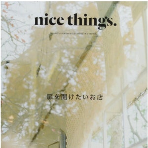 May include: A magazine cover with the title "nice things." The magazine is about good life with nice things. The cover features a blurry image of a shop front with a sign that reads "扉を開けたいお店" which translates to "I want to open the door to the store." The magazine is titled "GOOD STORES."