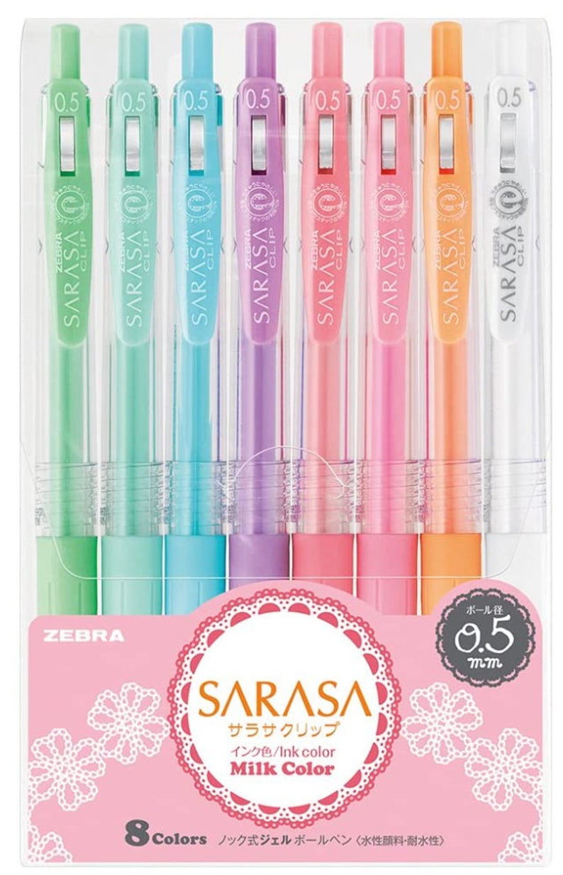 May include: A set of eight Zebra Sarasa Clip gel pens in pastel colors. The pens are 0.5 mm and have a clear barrel with a colored ink cartridge. The packaging features a pink background with a white lace design and the text "Sarasa Clip" in Japanese and English. The text "Milk Color" is also featured on the packaging.