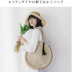 以下が含まれることがあります： ベージュの麦わら帽子と黒いタッセルが付いた丸いベージュの麦わらバッグが写る本の表紙。テキストは「大人のための、スタイリッシュデザイン30」「エコアンダリヤの帽子＆かごバッグ」「30 designs of bag and hat」「朝日新聞出版」と記載されています。