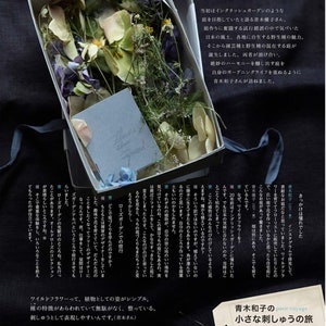 May include: An open white box filled with dried flowers in shades of purple, green, and cream, with a small card that reads "flowers bloom in my mind." A blue ribbon is tied around the box.