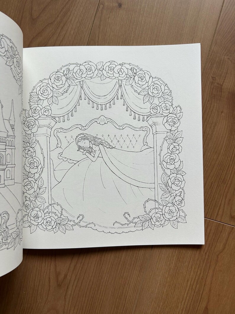 Op de afbeelding: Een zwart-wit kleurboekpagina met een lijntekening van een persoon die in een bed slaapt onder een rozenbaldakijn. De sc&egrave;ne wordt omlijst door een boog van bloeiende rozen en bladeren, met aan de linkerkant een kasteel zichtbaar.