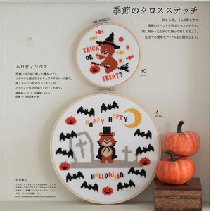 May include: Two cross-stitch hoops with Halloween themes. One features a bear in a witch hat with the words "Trick or Treat." The other has a bear in a top hat with the word "Halloween." Orange pumpkins and bats are also featured.