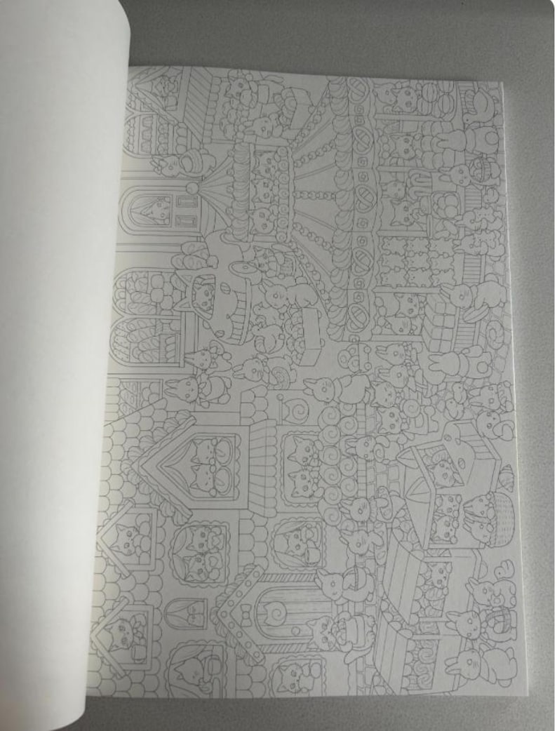 May include: A partially open coloring book featuring detailed line art illustrations. The drawings depict a whimsical scene with houses, animals, and various decorative elements. The pages are white, and the illustrations are in black and white.