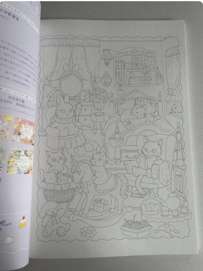 May include: A detailed line drawing of a coloring book page featuring a bedroom scene with animal characters. A bunny sits at a vanity, a cat reads a book, and a unicorn rocking horse is present. The text on the left side is in Japanese.