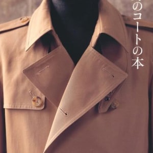 May include: A tan trench coat with a double breasted closure and a large collar. The coat has a button on the left side of the chest and two buttons on the bottom.