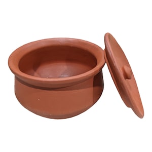 Puede incluir: Una olla de cocción de terracota con tapa. La olla es de color marrón rojizo y tiene una forma redondeada. La tapa es ligeramente abovedada y tiene un pequeño pomo en la parte superior.