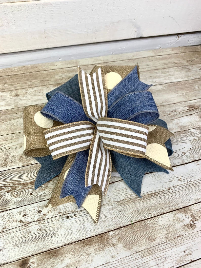 Puede incluir: Un lazo de cinta marr&oacute;n, blanco y azul con patrones de lunares y rayas. El lazo est&aacute; atado en un nudo y los extremos est&aacute;n extendidos.