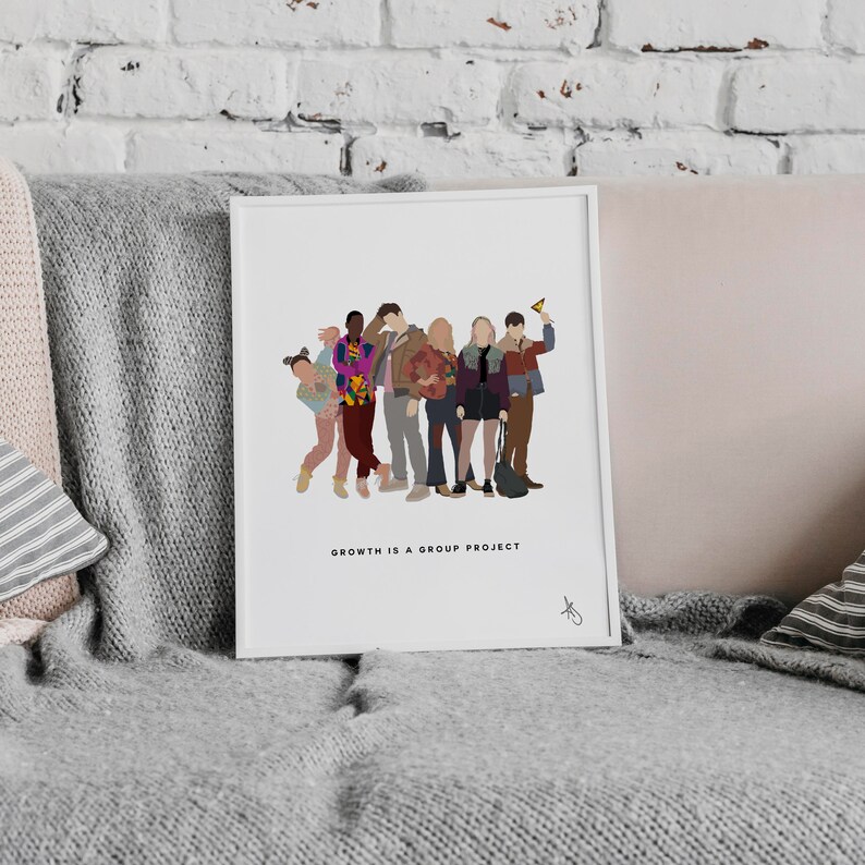 May include: A white framed print with a group of seven people standing together. The people are wearing colorful clothing and the print has the text "Growth is a group project".