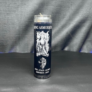 May include: A black glass candle with a white label that reads "King Asmodeus" and a white image of a demon with a crown. The label also includes the text "Ater - Avage - Aloren Asmodeus - Aken".