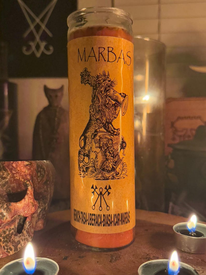 K&ouml;nnte beinhalten: Eine gelbe und orangefarbene Kerze mit einem Schwarzwei&szlig;bild eines L&ouml;wen, der eine Trompete h&auml;lt. Die Kerze tr&auml;gt den Aufdruck "MARBAS" und den Text "RENOVIL-TASA-UBERACA-BIASA-ICAR-MARBAS" am Boden.