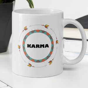 May include: White ceramic mug with a colorful geometric design and the word "KARMA" in black text.